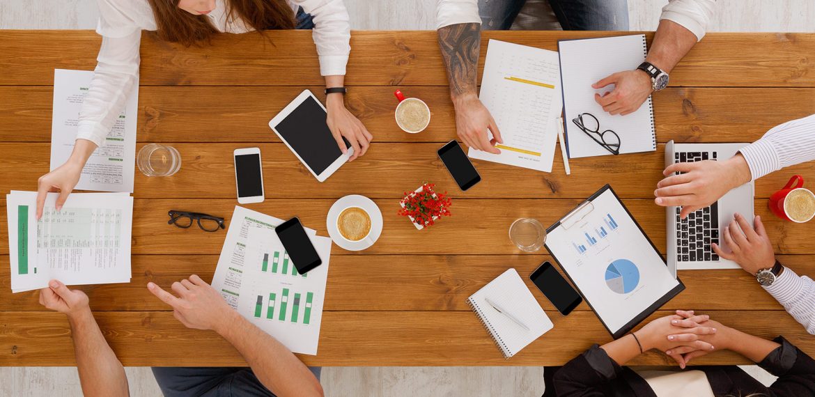 Equipe trabalha em conjunto em uma agência para analisar dados e propor plano de marketing para empresa