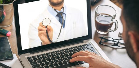 Homem busca informações sobre saúde pela internet e aparece na tela do notebook um médico